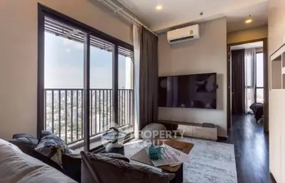 Modern living room with city view, large TV, and stylish decor in high-rise apartment.