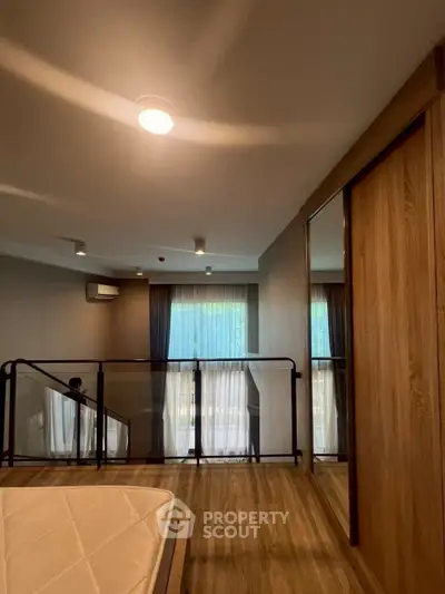 Modern bedroom with wooden flooring and large windows in a stylish apartment.
