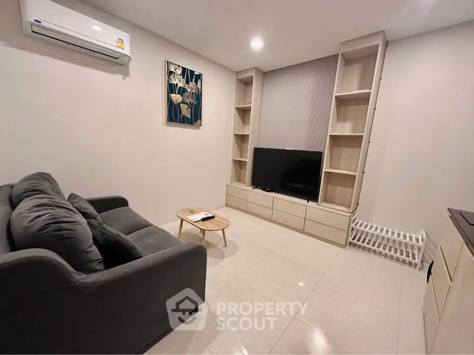 Modern living room with sleek furniture and wall-mounted air conditioning unit.