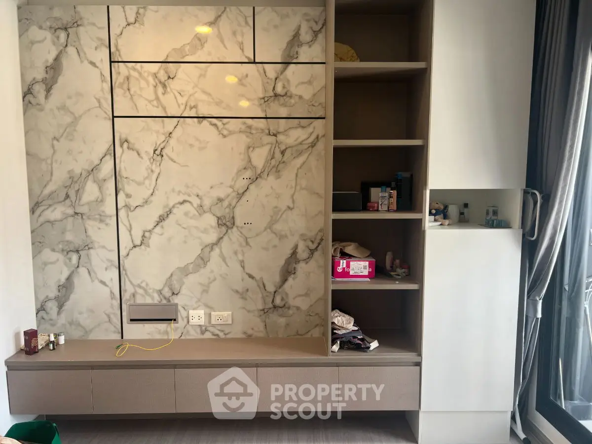 Modern living room with marble accent wall and built-in shelving unit.