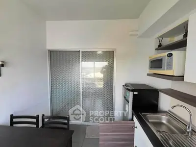Modern kitchen with sleek appliances and dining area in a compact layout.