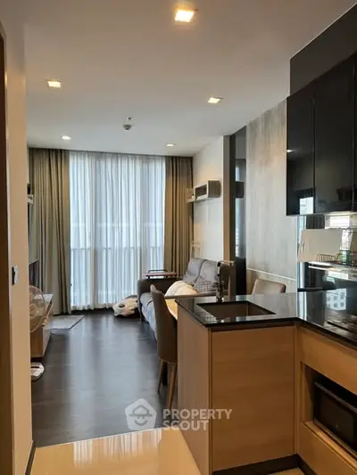 Modern open-layout apartment with sleek kitchen and cozy living area, featuring floor-to-ceiling windows.
