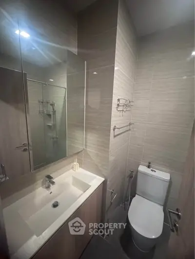 Modern bathroom with sleek fixtures and elegant tile design, featuring a spacious mirror and contemporary sink.