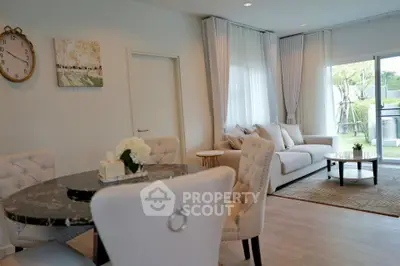 Elegant living room with plush seating and dining area, featuring large windows and stylish decor.