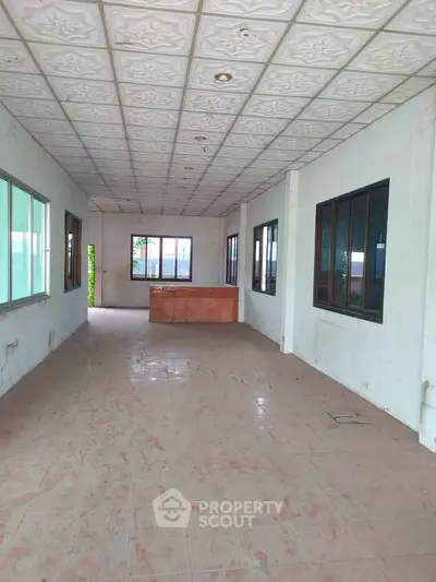 Spacious empty room with tiled floor and large windows, ideal for customization.