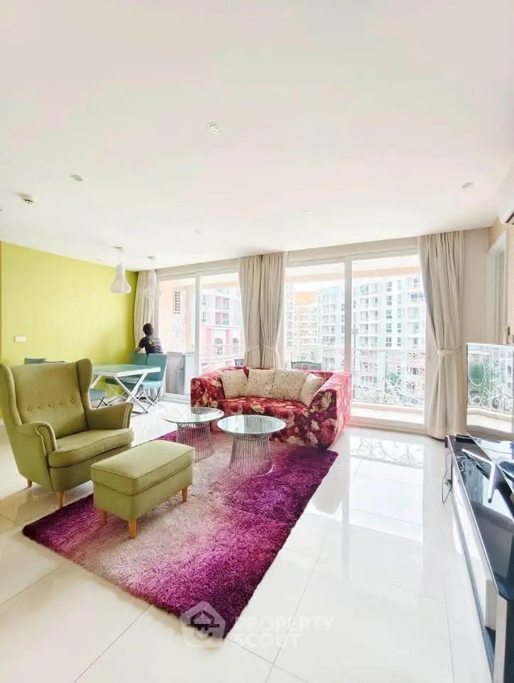Spacious living room with vibrant decor and large windows offering city views.
