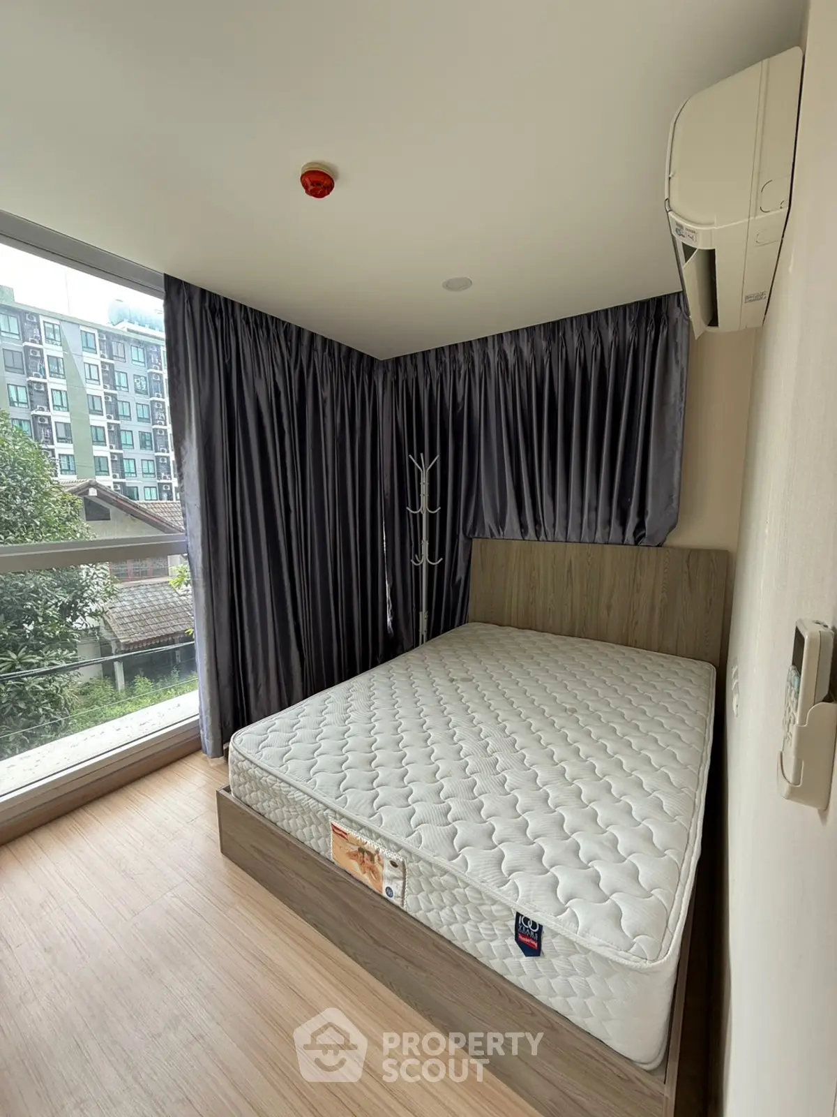 Modern bedroom with large window and air conditioning in urban apartment