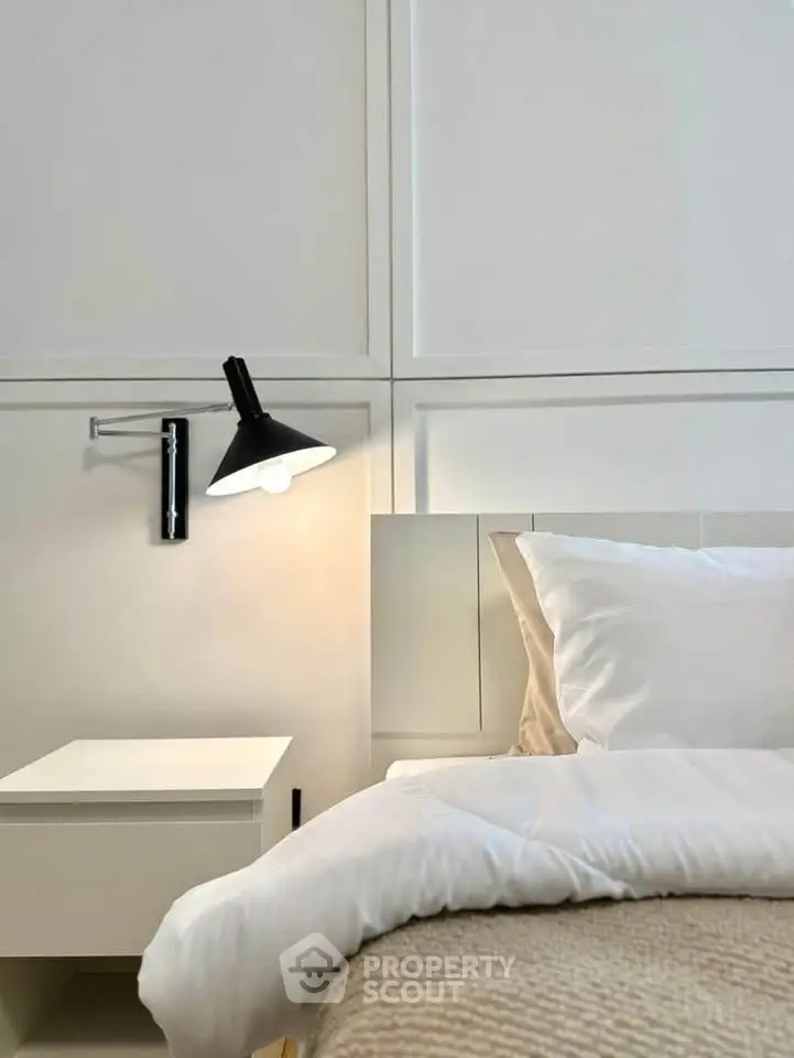 Modern bedroom with sleek wall lamp and cozy bedding