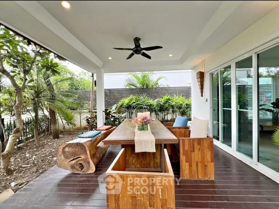 Charming outdoor patio with wooden furniture and lush greenery, perfect for relaxation and entertaining.
