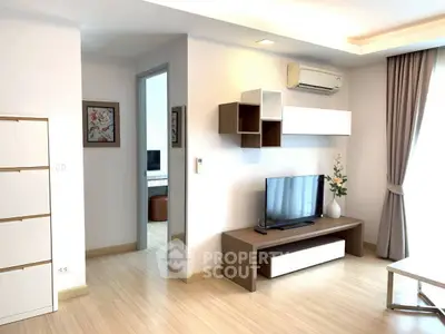Modern living room with sleek furniture and natural light, featuring a wall-mounted TV and air conditioning.