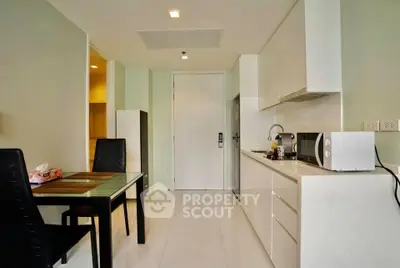 Modern kitchen with sleek white cabinets and dining area in a stylish apartment.
