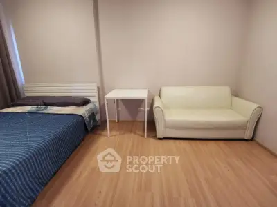 Cozy bedroom with bed, sofa, and small table on wooden floor