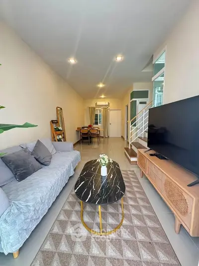 Modern living room with stylish furniture and open layout, featuring a large TV and cozy seating area.