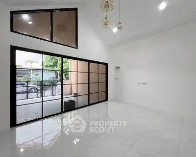 Spacious modern living room with large windows and elegant lighting fixtures.
