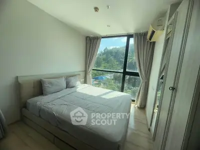 Bright bedroom with large window and scenic view, featuring modern furnishings and natural light.