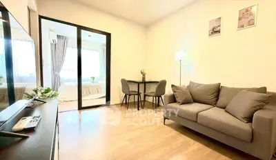 Modern living room with cozy sofa and dining area, featuring a view into a bright bedroom.