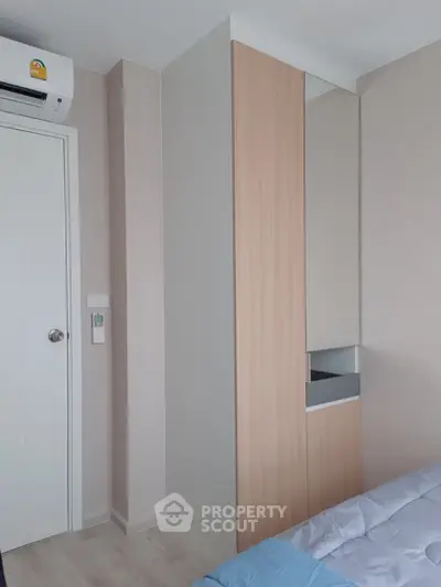 Modern bedroom with sleek built-in wardrobe and air conditioning unit, showcasing minimalist design.
