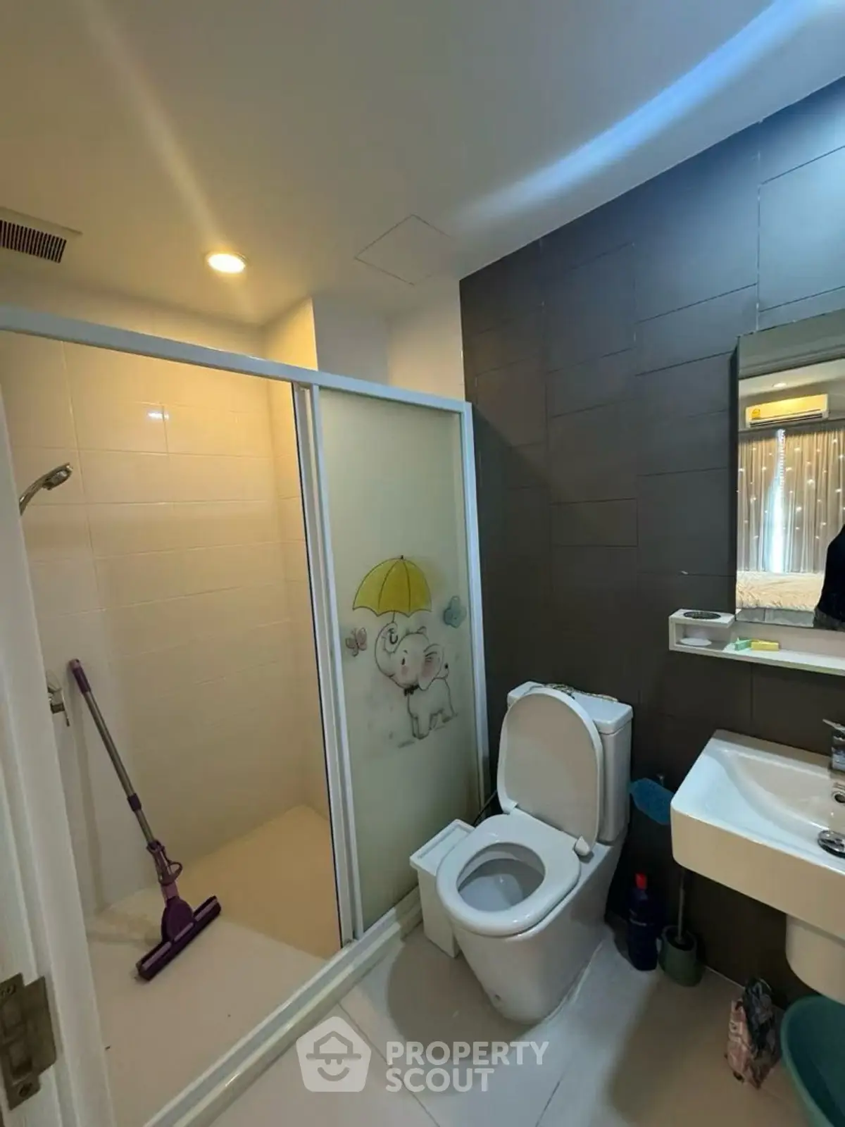 Modern bathroom with shower, toilet, and sink in a cozy apartment setting.