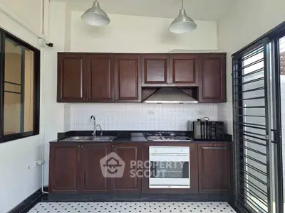 Modern kitchen with dark wood cabinets and white appliances in a bright space.