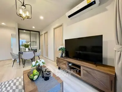 Modern living room with stylish decor and dining area, featuring a large TV and elegant lighting.