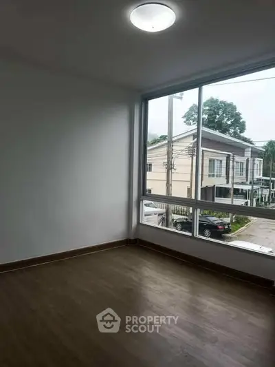 Spacious empty room with large window and street view, perfect for customization.