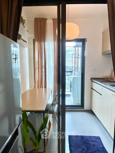 Modern kitchen with open layout and balcony view, featuring sleek cabinetry and natural light.