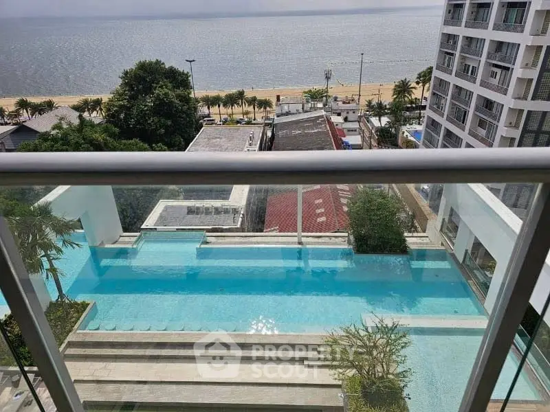 Stunning beachfront view from a high-rise balcony overlooking a luxurious pool and ocean.