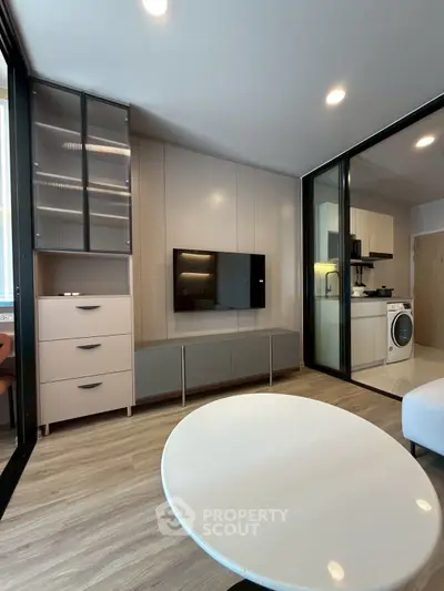 Modern living room with sleek furniture and integrated kitchen appliances in a stylish apartment.