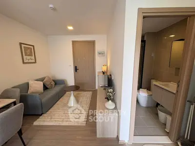 Modern living room with cozy sofa and stylish decor adjacent to a compact bathroom.