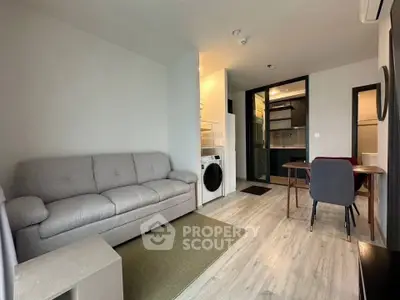 Modern living room with washing machine and dining area in open layout apartment.