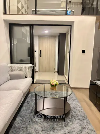 Modern living room with sleek design, glass coffee table, and cozy gray sofa in a stylish apartment.