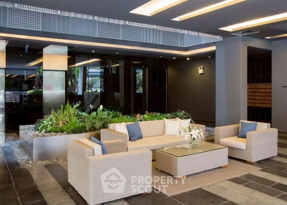 Luxurious modern building entrance with elegant seating and lush greenery.