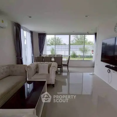 Spacious modern living room with elegant furniture and large windows offering garden views.