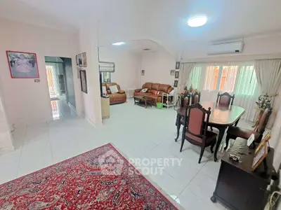 Spacious living room with elegant dining area and cozy seating, featuring large windows and classic decor.