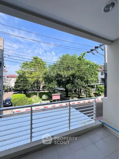 Spacious balcony with scenic view of lush greenery and clear blue sky, perfect for relaxation.