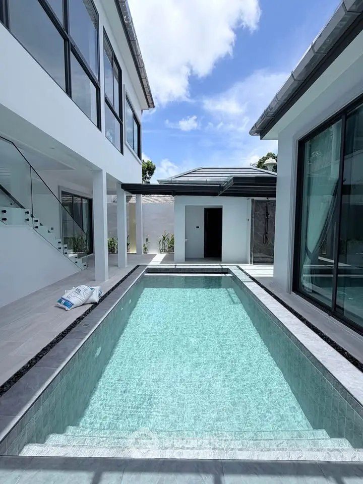 Luxurious modern home with sleek pool and elegant architecture under a clear blue sky.
