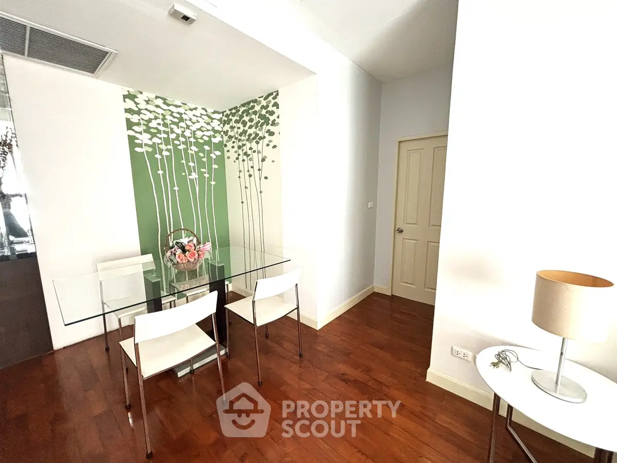 Stylish dining area with glass table and modern decor in a cozy apartment.
