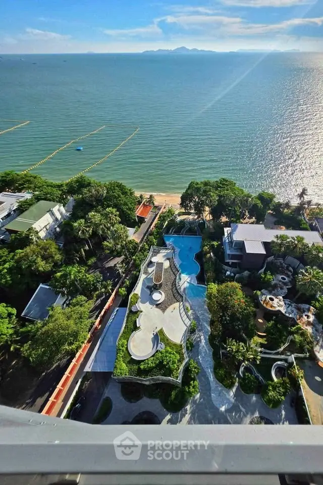 Stunning aerial view of beachfront property with lush gardens and ocean backdrop, perfect for luxury living.