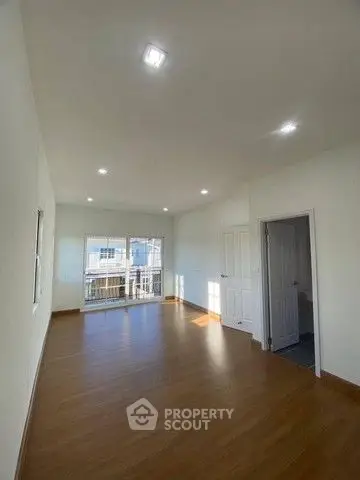Spacious empty room with wooden flooring and large windows for natural light.