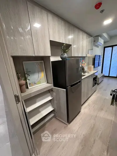 Modern kitchen with sleek cabinetry and stainless steel fridge in a stylish apartment.