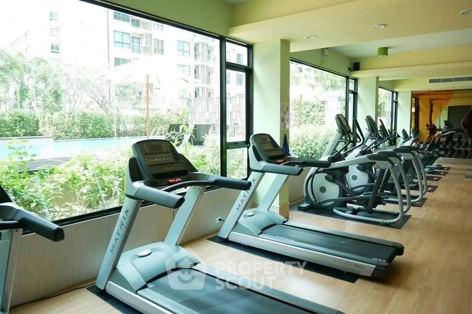 Modern gym with treadmills and pool view in luxury apartment complex