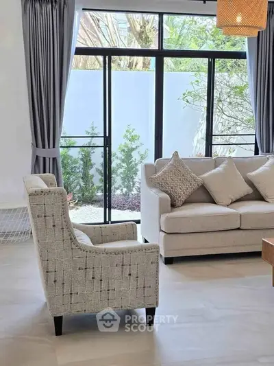 Elegant living room with modern furniture and large windows overlooking a serene garden.