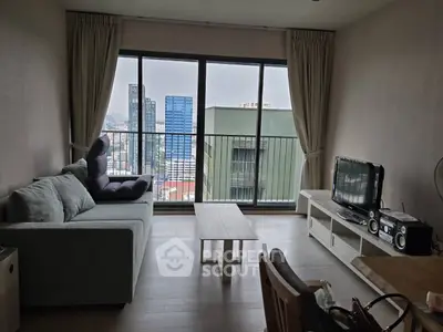 Modern living room with city view, featuring a cozy sofa, TV, and large windows for natural light.