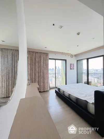 Spacious bedroom with city view and large windows, modern decor and natural light.