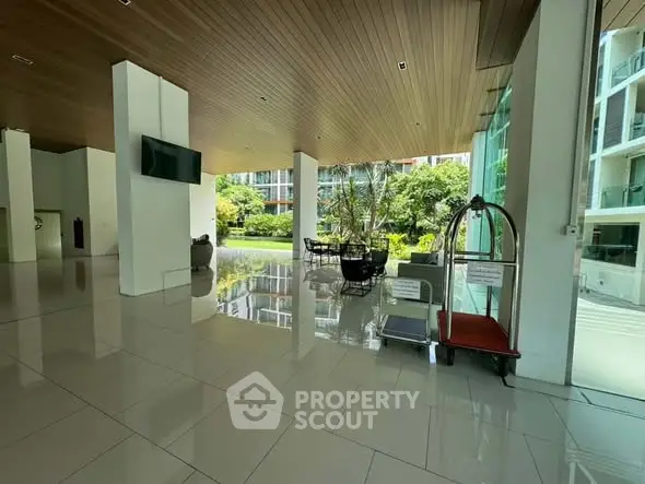 Spacious modern building entrance with sleek design and lush greenery view.