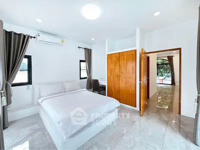 Spacious bedroom with modern design and ample natural light, featuring a cozy bed and built-in wardrobe.