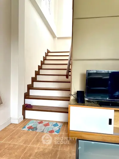 Modern interior with stylish staircase and entertainment unit in a bright living space.