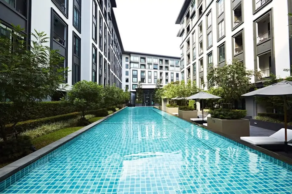 Luxurious apartment complex with a stunning outdoor pool and modern architecture.