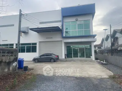 Modern commercial building with spacious parking area and large glass windows.