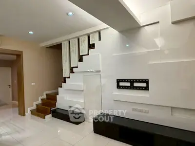 Modern interior with sleek staircase and wall-mounted TV setup in stylish living room.